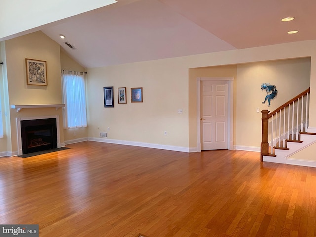 unfurnished living room with wood-type flooring and vaulted ceiling