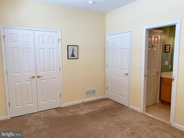 unfurnished bedroom featuring ensuite bathroom and light colored carpet