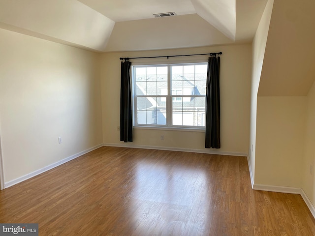 empty room featuring vaulted ceiling and light hardwood / wood-style floors