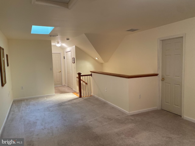 interior space featuring vaulted ceiling with skylight and light carpet