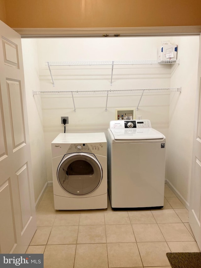 clothes washing area with separate washer and dryer and light tile patterned floors