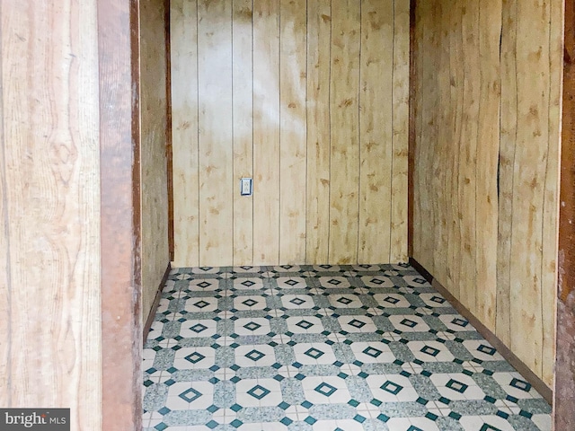 unfurnished room featuring wooden walls