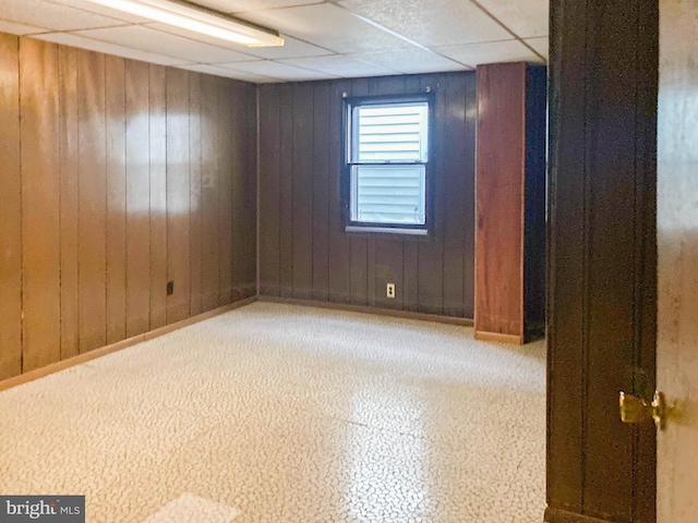 empty room featuring wooden walls and a paneled ceiling