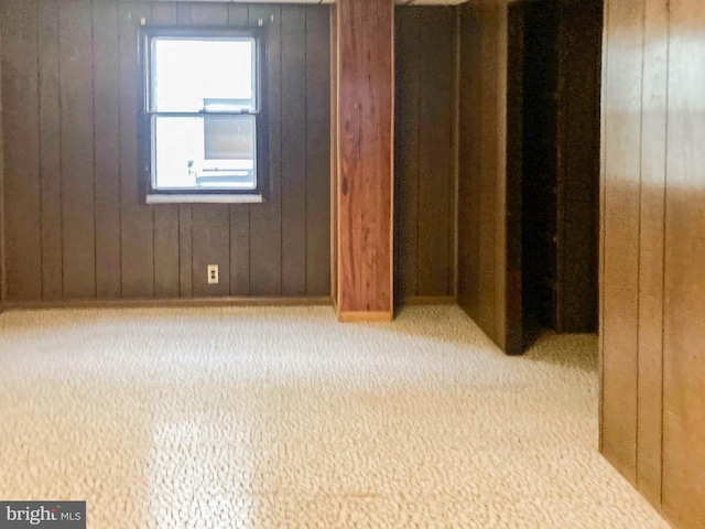 carpeted empty room featuring wood walls