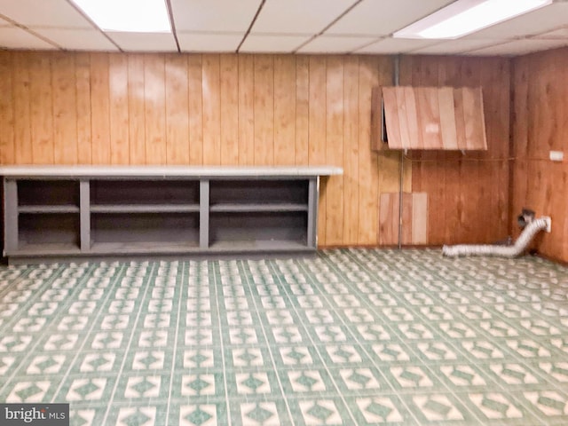 interior space featuring wooden walls and a drop ceiling