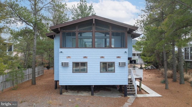 view of front of home with fence, a sunroom, stairs, an AC wall unit, and a carport