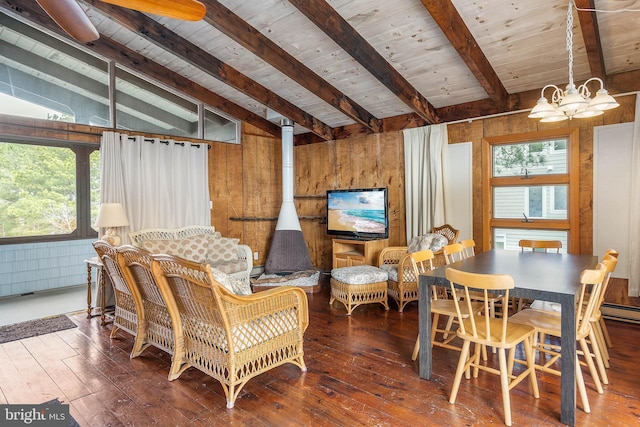 dining area featuring hardwood / wood-style flooring, a wood stove, vaulted ceiling with beams, and wood walls