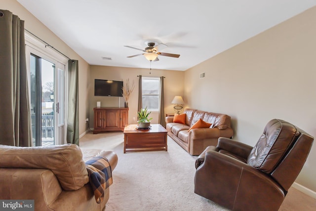 living area with visible vents, light colored carpet, baseboards, and a ceiling fan