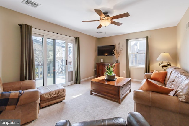 living room featuring a ceiling fan, baseboards, visible vents, and light carpet