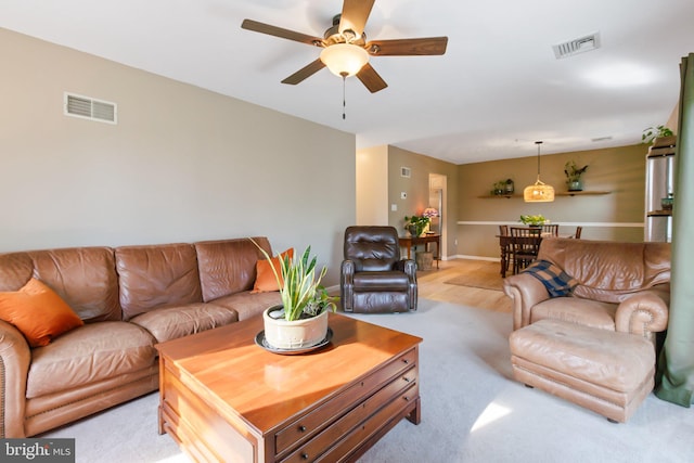 living area featuring visible vents, baseboards, and ceiling fan