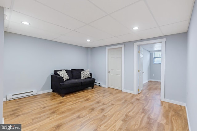 living area with recessed lighting, a baseboard heating unit, baseboards, and light wood finished floors