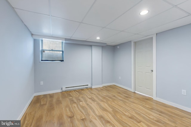 below grade area featuring light wood finished floors, a baseboard heating unit, and baseboards