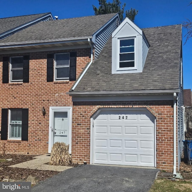 view of front facade featuring brick siding, driveway, and roof with shingles