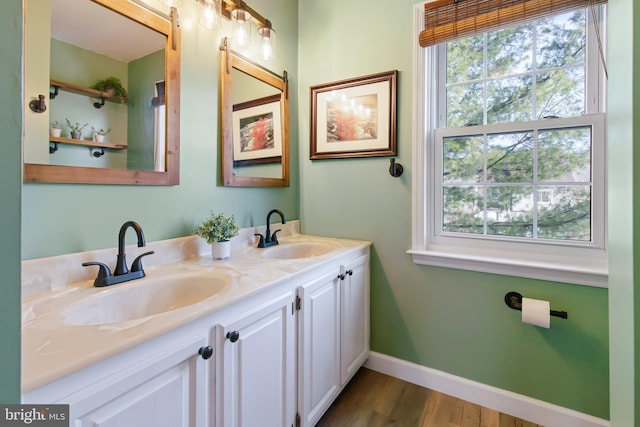 full bath featuring double vanity, wood finished floors, baseboards, and a sink