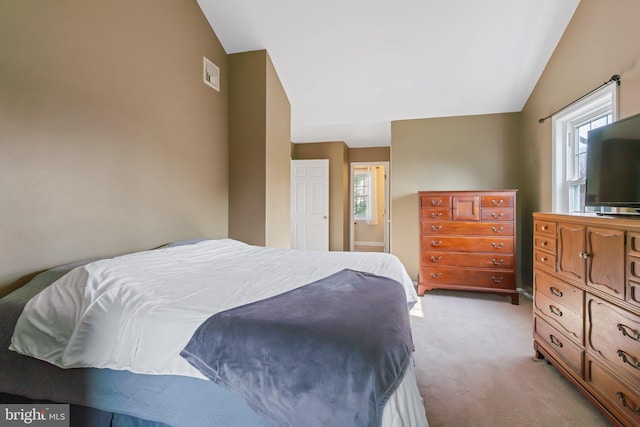 bedroom with visible vents, light colored carpet, and vaulted ceiling