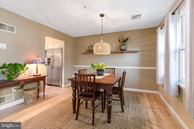 dining area with light wood finished floors, visible vents, and baseboards