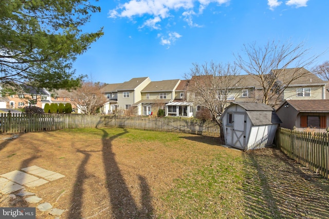 view of yard featuring a residential view, an outbuilding, a fenced backyard, and a shed