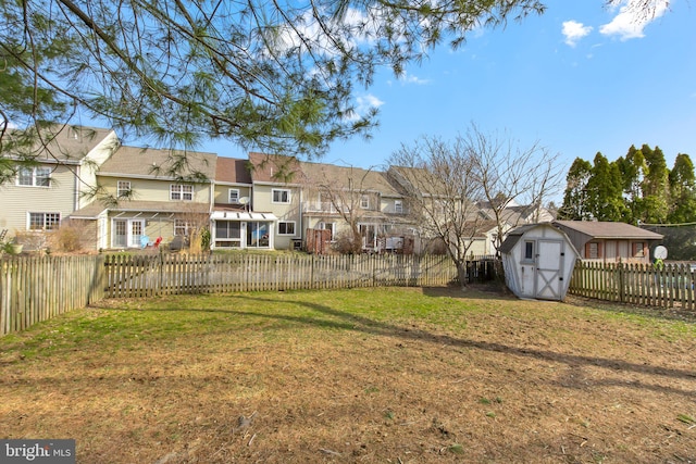 view of yard featuring a residential view, an outdoor structure, a storage shed, and a fenced backyard