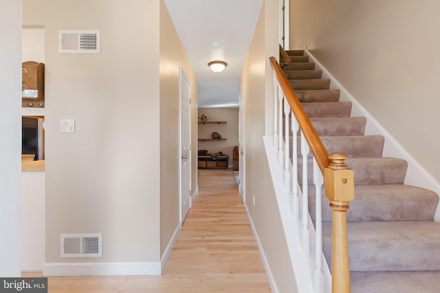 staircase with visible vents, baseboards, and wood finished floors