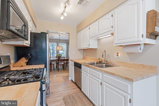 kitchen with visible vents, wooden counters, a sink, appliances with stainless steel finishes, and white cabinetry