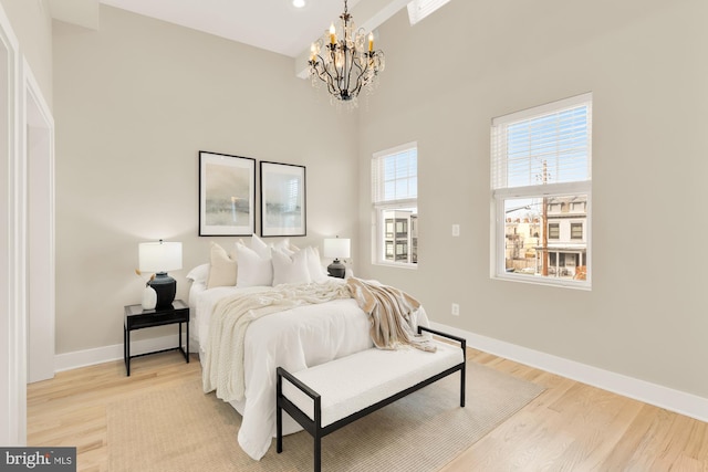 bedroom with light wood-style flooring, baseboards, and an inviting chandelier