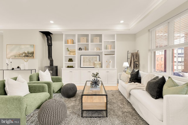 living area featuring ornamental molding, recessed lighting, a wood stove, and light wood finished floors