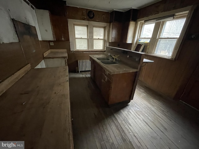 kitchen featuring radiator, wood walls, sink, hardwood / wood-style flooring, and a center island