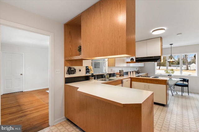 kitchen with decorative light fixtures, dishwasher, white cabinetry, sink, and kitchen peninsula