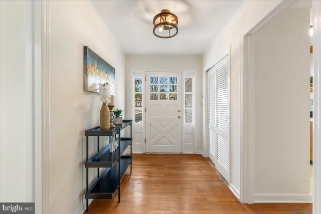 foyer entrance with crown molding and hardwood / wood-style floors