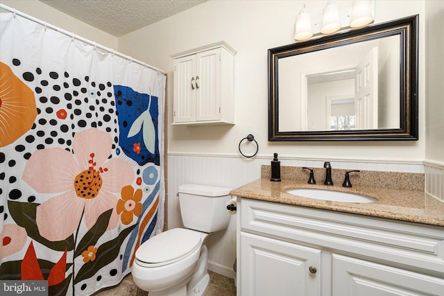 bathroom featuring vanity, a textured ceiling, and toilet