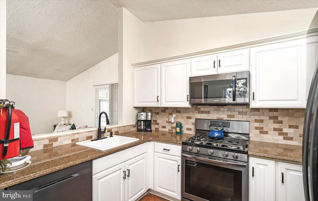 kitchen featuring sink, appliances with stainless steel finishes, backsplash, white cabinets, and vaulted ceiling