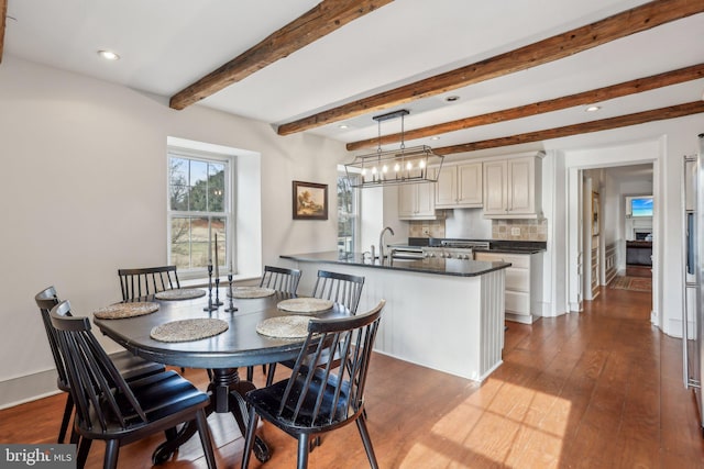 dining room featuring hardwood / wood-style flooring, sink, an inviting chandelier, and beam ceiling