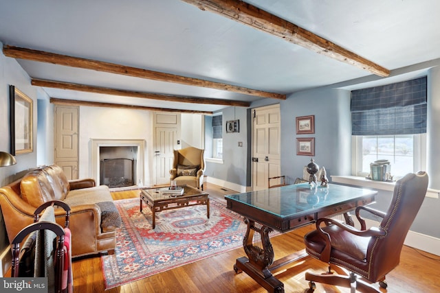 living room featuring beamed ceiling and light hardwood / wood-style flooring