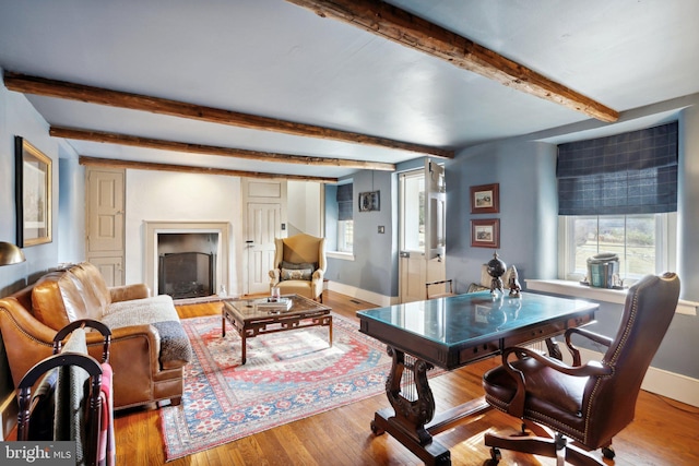 living room featuring beam ceiling, light hardwood / wood-style flooring, and a healthy amount of sunlight