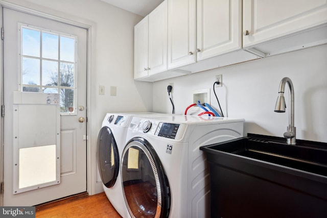 laundry area featuring cabinets, sink, washing machine and dryer, and light wood-type flooring