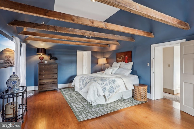 bedroom with hardwood / wood-style floors and beam ceiling