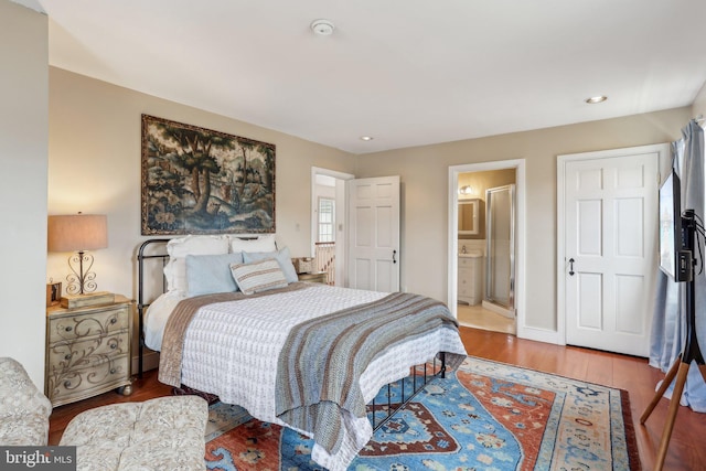 bedroom with connected bathroom and hardwood / wood-style floors