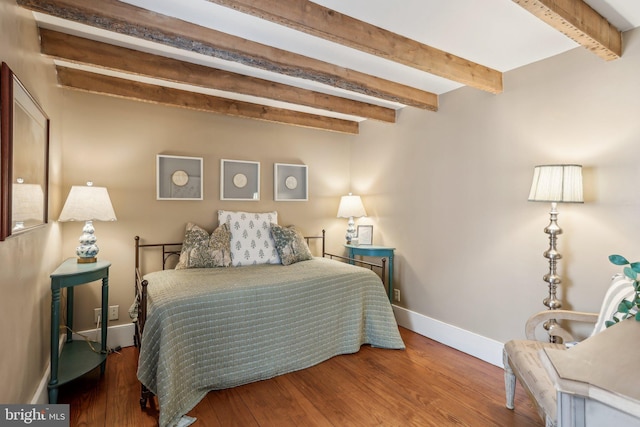 bedroom with hardwood / wood-style floors and beam ceiling