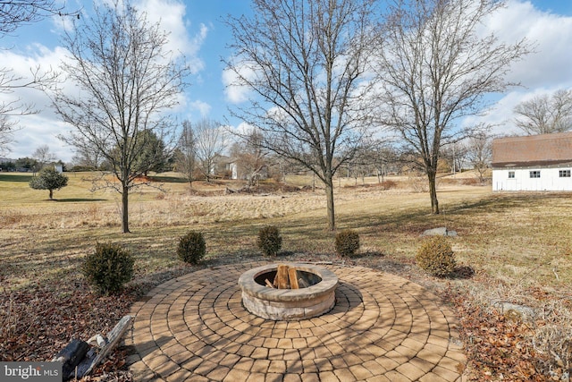 view of patio / terrace with an outbuilding, a fire pit, and a rural view