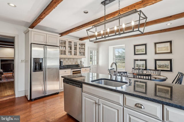 kitchen featuring white cabinetry, stainless steel appliances, decorative light fixtures, and sink