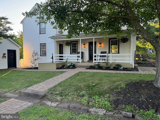 view of front of home featuring a porch, an outbuilding, and a front yard