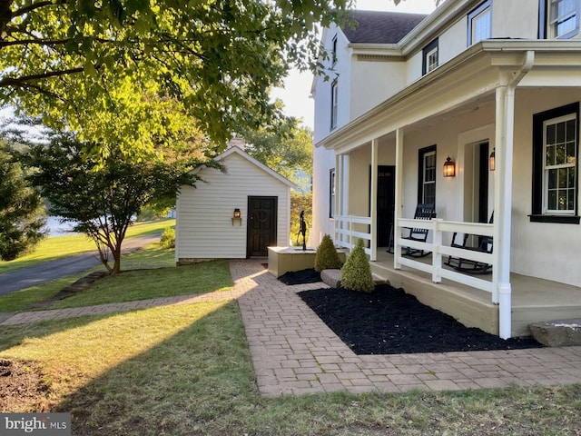 property entrance featuring a lawn and a porch