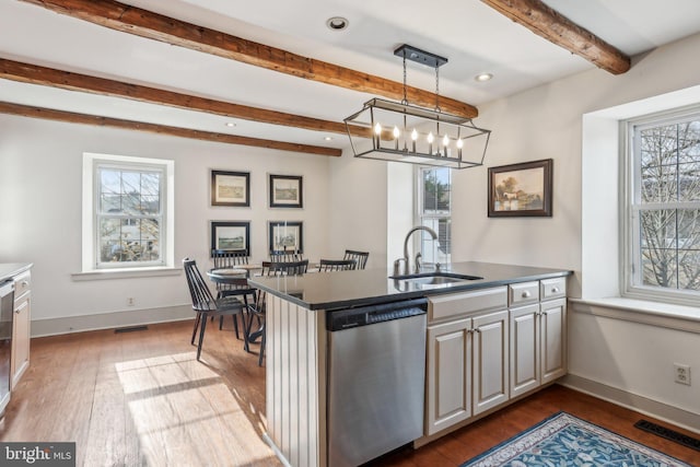 kitchen with sink, stainless steel dishwasher, dark hardwood / wood-style floors, pendant lighting, and beam ceiling