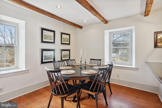 dining space with hardwood / wood-style flooring and beamed ceiling