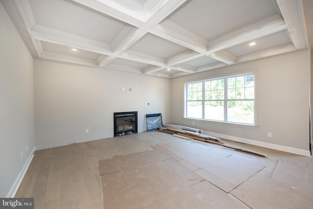 unfurnished living room featuring baseboards, coffered ceiling, beam ceiling, and a glass covered fireplace