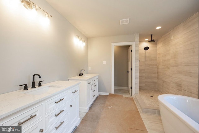 bathroom featuring two vanities, a sink, and a tile shower