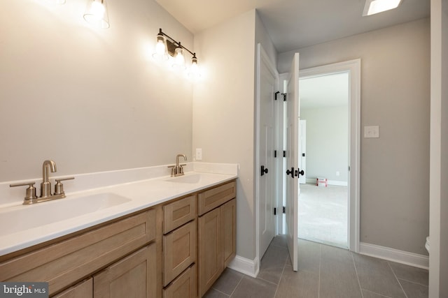 bathroom with double vanity, a sink, baseboards, and tile patterned floors