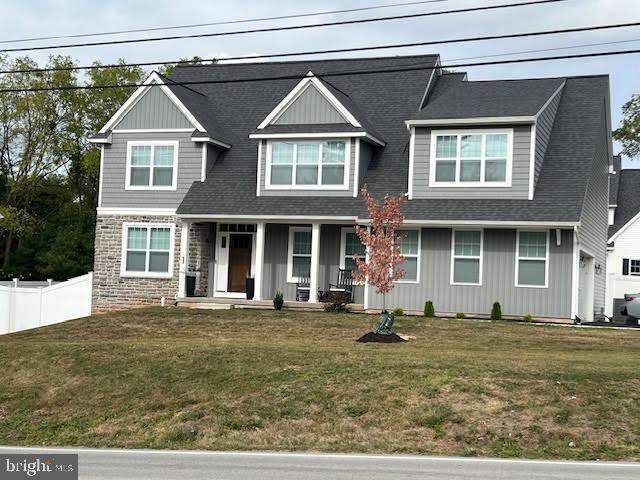 craftsman-style home featuring a porch, a front yard, and fence