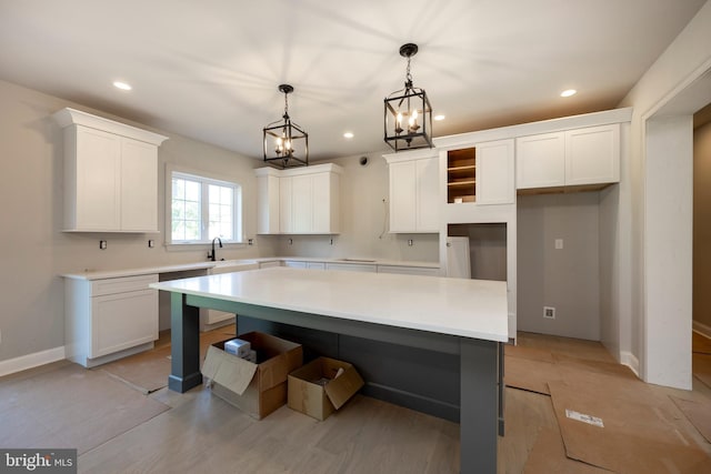 kitchen with hanging light fixtures, a kitchen island, sink, and white cabinets