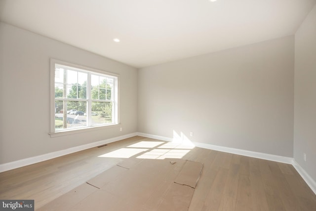 unfurnished room featuring visible vents, baseboards, and wood finished floors